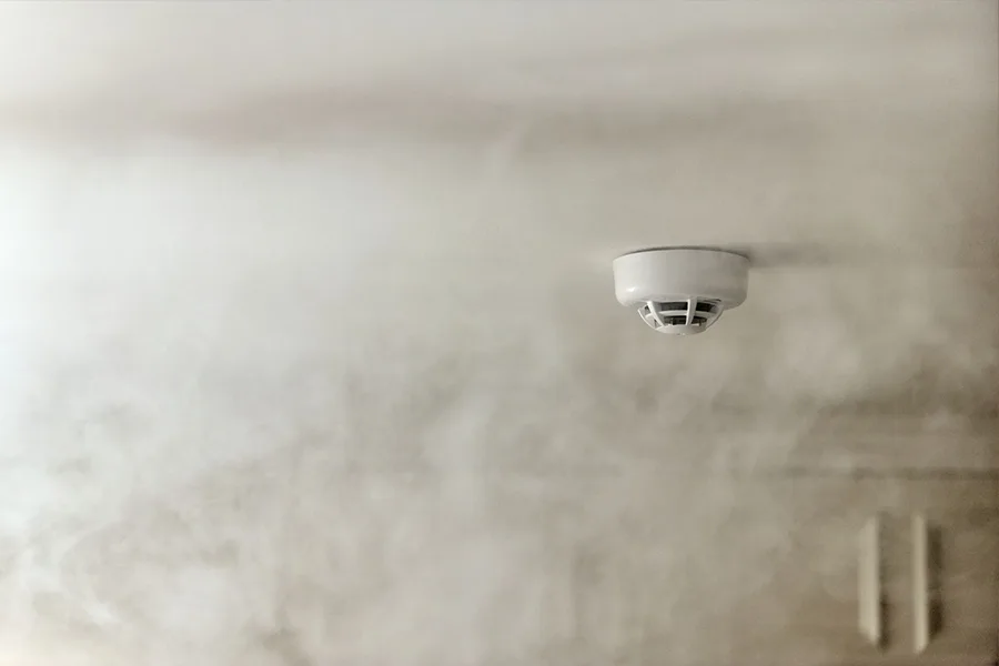 Vivint's Smoke & CO Detector attached to a ceiling and surrounded by smoke.